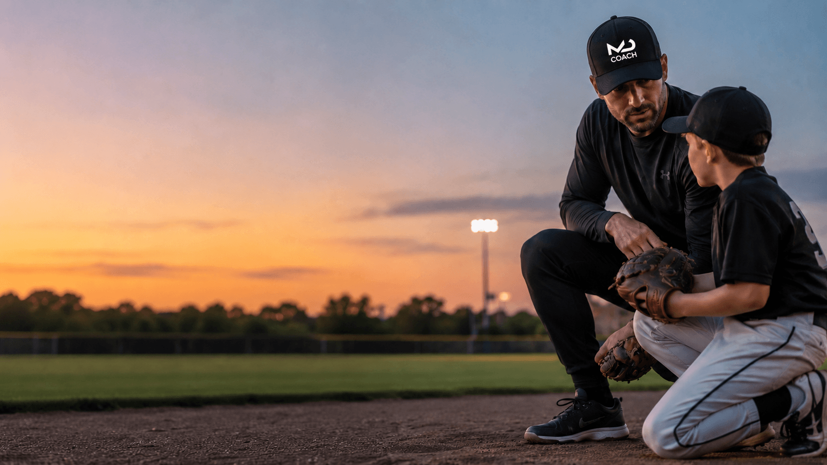 Modern Day Coach working with a young baseball player during an evening practice.